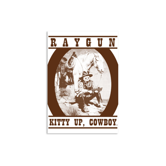 A RAYGUN graphic poster featuring a cowboy with a cat head holding a rifle next to a horse, with the text KITTY UP, COWBOY at the bottom.