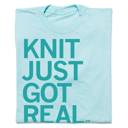 Light blue RAYGUN t-shirt with the text KNIT JUST GOT REAL printed in dark teal.