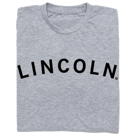 Folded heather grey crewneck t-shirt with LINCOLN printed in black, arched letters across the chest.