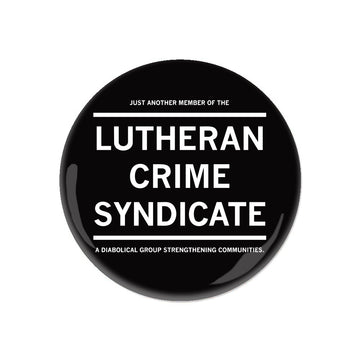 Black circular Lutheran Crime Syndicate button that reads: JUST ANOTHER MEMBER OF THE LUTHERAN CRIME SYNDICATE A DIABOLICAL GROUP STRENGTHENING COMMUNITIES.