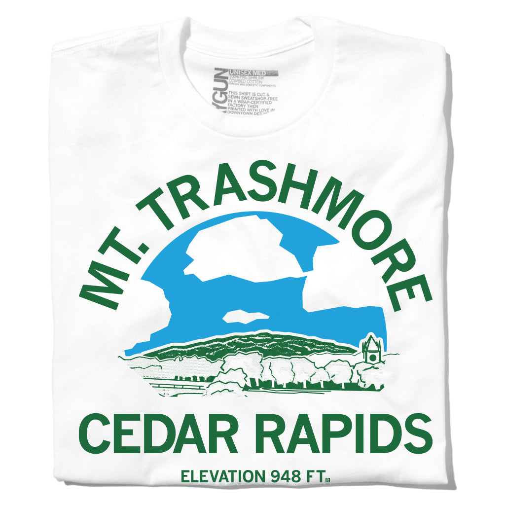 White t-shirt with a green and blue graphic of the Mount Trashmore hill in Cedar Rapids, featuring the text MT. TRASHMORE CEDAR RAPIDS ELEVATION 948 FT above a stylized illustration of the landmark.