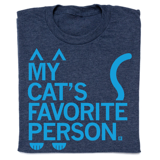 Heather denim navy blue t-shirt with light blue text reading MY CATS FAVORITE PERSON, featuring graphic cat ears at the top, a tail on the right, and paw prints at the bottom.