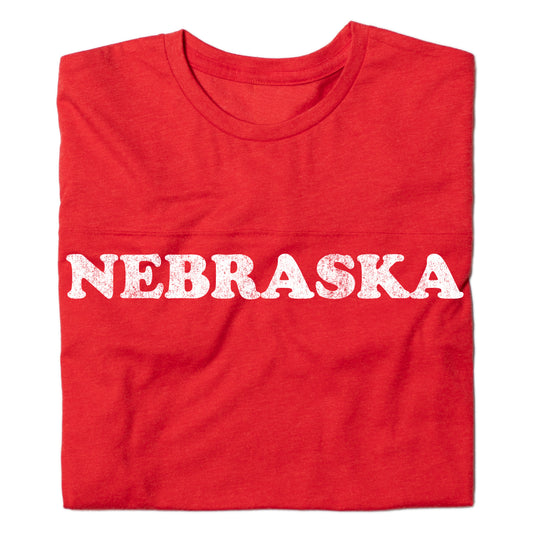 Folded vintage Nebraska red jersey t-shirt with NEBRASKA printed in white distressed lettering across the chest.