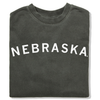 Folded charcoal gray RAYGUN crewneck sweatshirt with the word NEBRASKA printed in white arching across the chest.