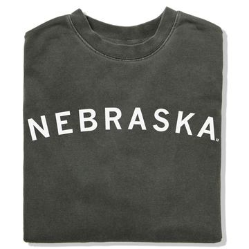 Folded charcoal gray RAYGUN crewneck sweatshirt with the word NEBRASKA printed in white arching across the chest.