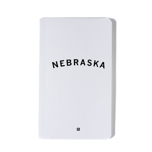 White notebook with Nebraska printed in black screen print and a small R logo at the bottom.