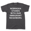Dark gray union-made t-shirt featuring the white text NEBRASKA STANDS WITH OUR IMMIGRANT NEIGHBORS in support of Nebraska immigrant communities.