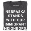 Dark gray union-made t-shirt featuring the text NEBRASKA STANDS WITH OUR IMMIGRANT NEIGHBORS in white block letters.