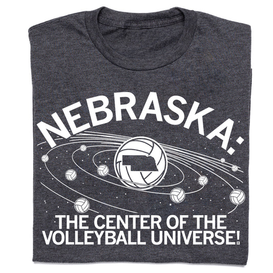 Charcoal T-shirt featuring a volleyball graphic with the state of Nebraska at the center of planetary rings, surrounded by smaller volleyballs and the text NEBRASKA: THE CENTER OF THE VOLLEYBALL UNIVERSE!.