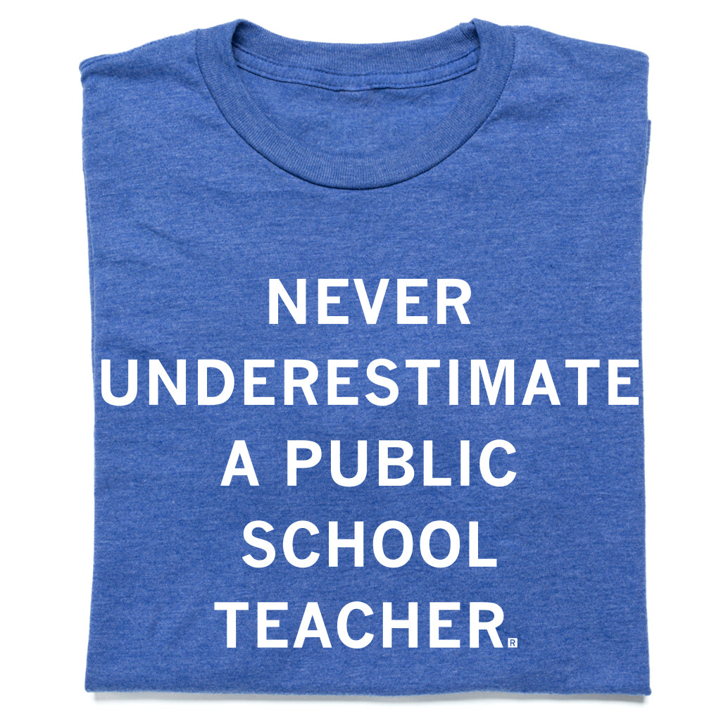 A heather royal blue t-shirt whit centered white text that says, "Never Underestimate a Public School Teacher" in all caps.
