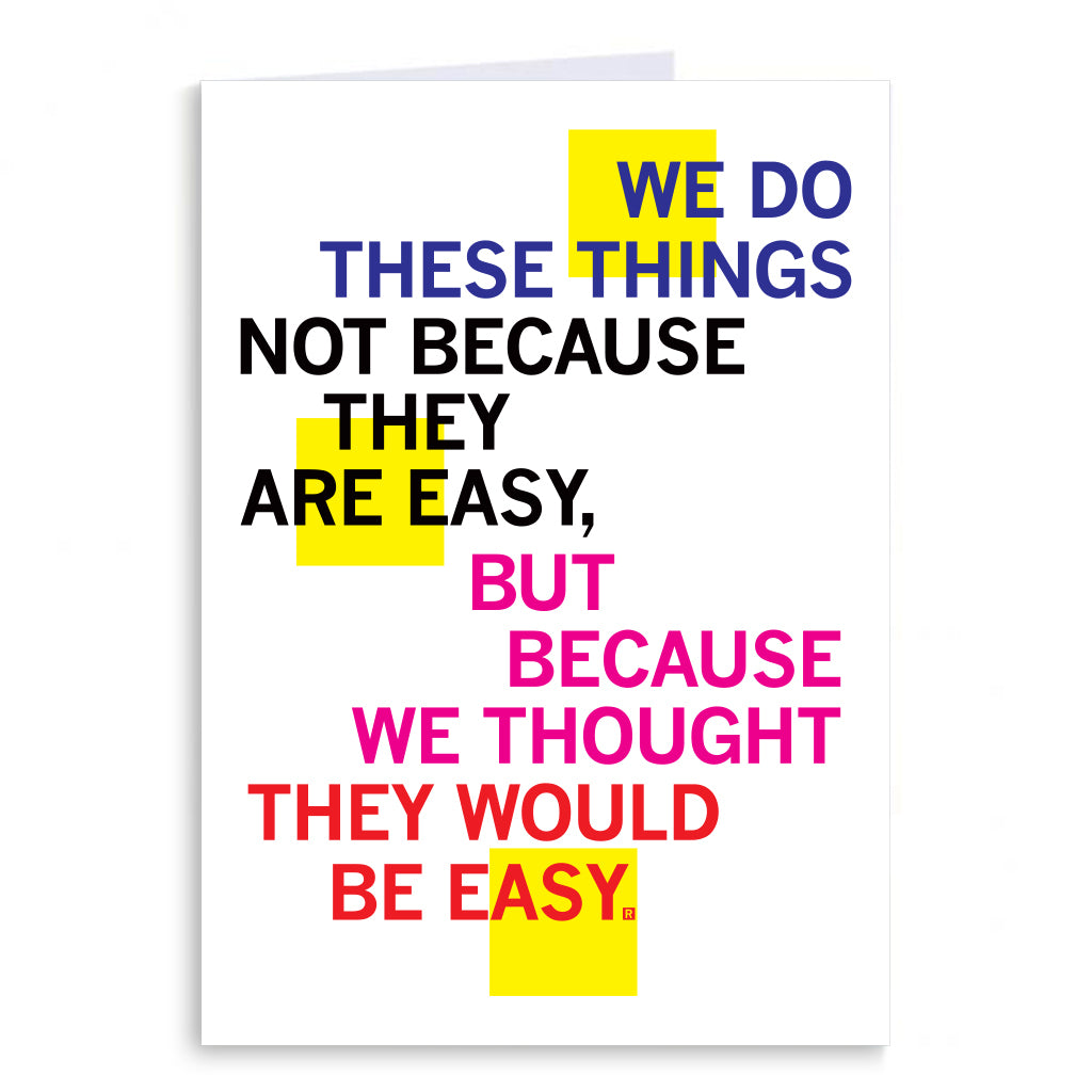 A folded greeting card featuring the text: WE DO THESE THINGS NOT BECAUSE THEY ARE EASY, BUT BECAUSE WE THOUGHT THEY WOULD BE EASY.