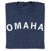A folded heather denim t-shirt with OMAHA printed in white capital letters across the chest.