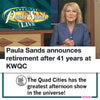 News anchor Paula Sands sits in front of a screen displaying her show’s logo and text announcing her retirement after 41 years at KWQC, while wearing a Paula Sands Live shirt to support the Norma Leah Ovarian Cancer Initiative.