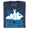 Heather denim t-shirt featuring a white graphic of four rabbits in front of a city skyline, with the text SEE THE RABBITS below in light blue.