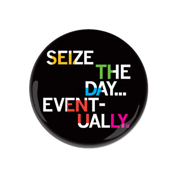 A round black RAYGUN metal button featuring the text SEIZE THE DAY... EVENTUALLY in multicolored letters.