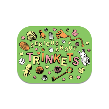 A RAYGUN die-cut vinyl sticker with the text SERIOUS ABOUT TRINKETS surrounded by various small objects including a seashell, dice, a thimble, a rubber duck, a skeleton hand, a key, and a small doll.