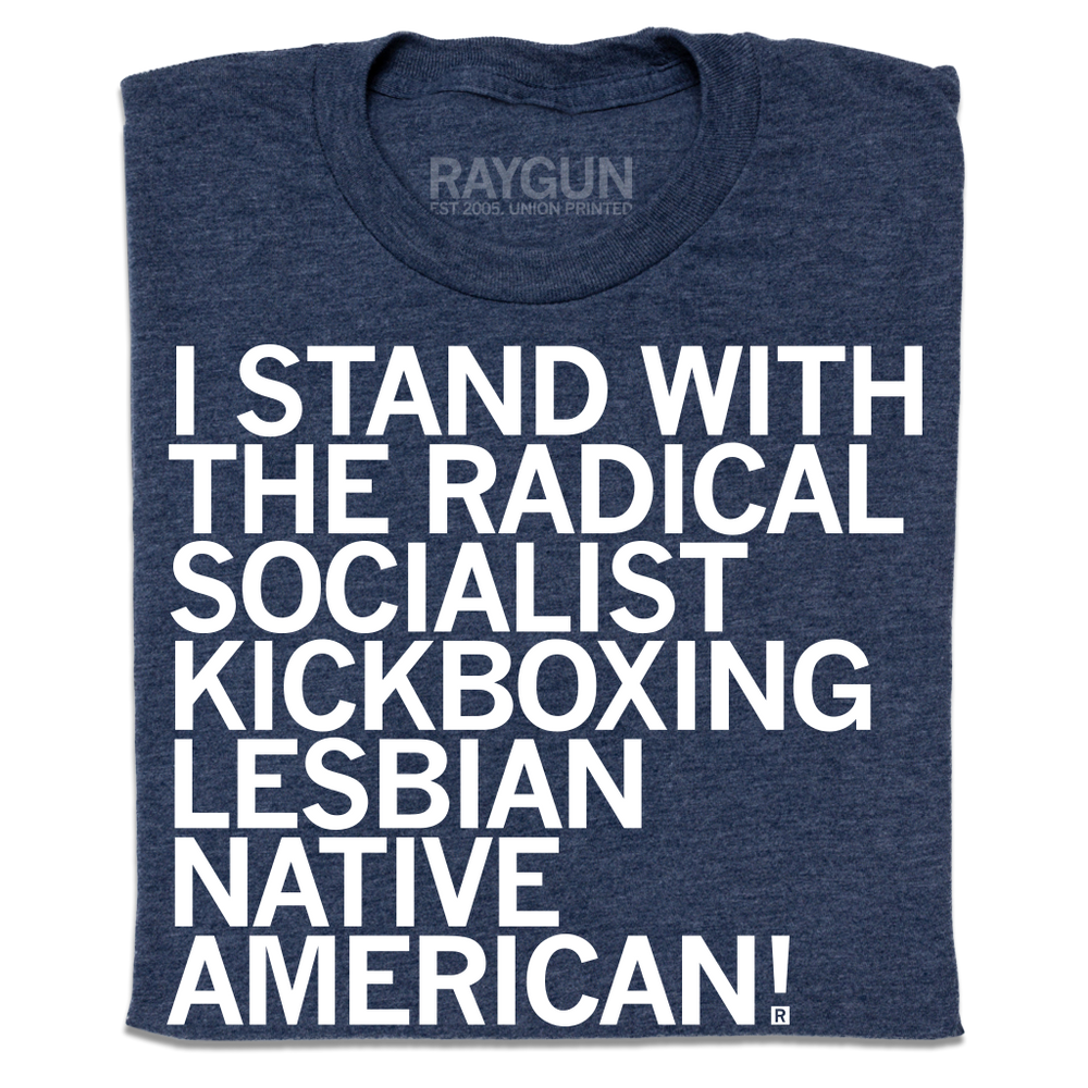 A folded heather navy t-shirt with left-aligned white ink text that reads "I stand with the radical socialist kickboxing lesbian Native American!"