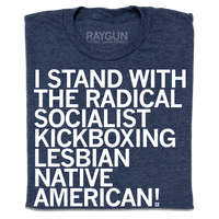 A folded heather navy t-shirt with left-aligned white ink text that reads "I stand with the radical socialist kickboxing lesbian Native American!"
