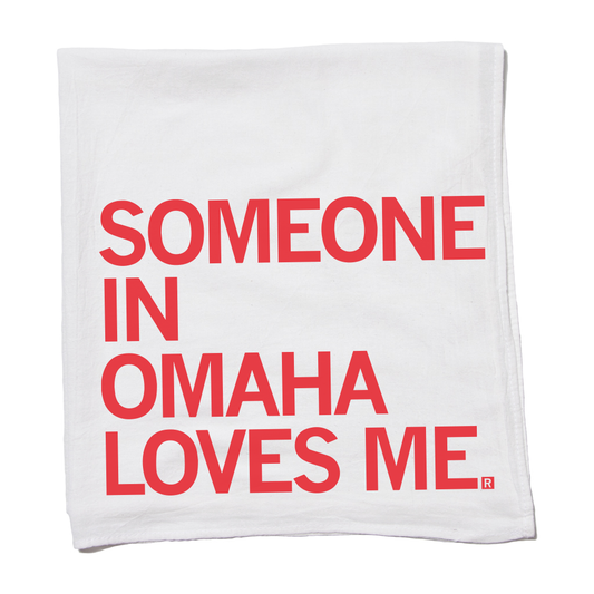 White flour sack kitchen towel with red text that reads, SOMEONE IN OMAHA LOVES ME.