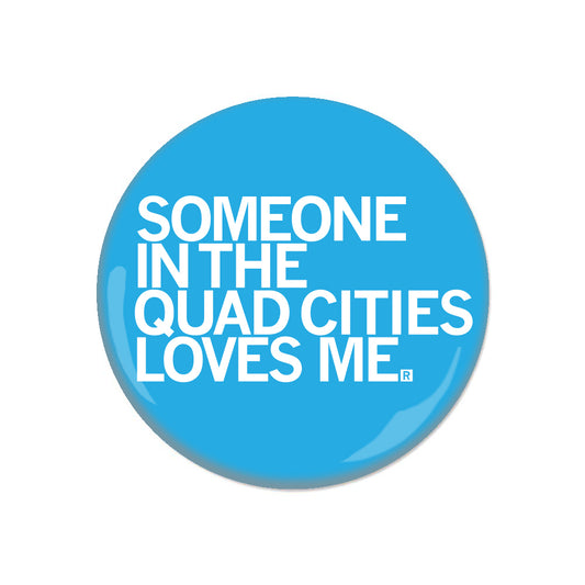 A round, blue RAYGUN metal button that reads SOMEONE IN THE QUAD CITIES LOVES ME.