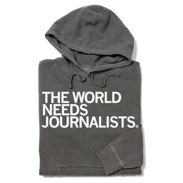 Charcoal grey, union-made pullover hoodie featuring the white text THE WORLD NEEDS JOURNALISTS.