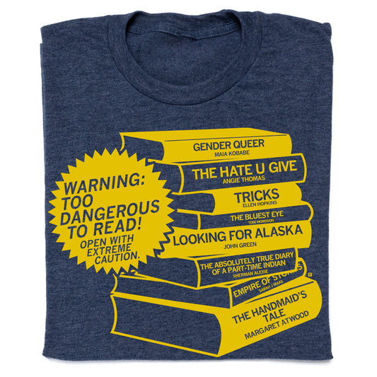 A union made, heather denim t-shirt featuring a yellow graphic of a book stack with titles of frequently challenged books and a starburst warning label that reads, Warning: Too dangerous to read! Open with extreme caution.