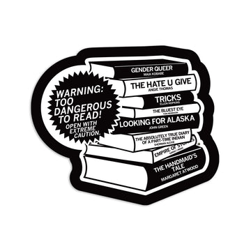 A RAYGUN vinyl sticker of a stack of books with a starburst label reading WARNING: TOO DANGEROUS TO READ! OPEN WITH EXTREME CAUTION, featuring titles like Gender Queer, The Hate U Give, The Bluest Eye, and The Handmaid’s Tale.