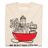 Cream-colored RAYGUN t-shirt featuring a graphic of a large red bowl filled with buildings and a Quaker Oats logo, with the text WE BUILT THIS CITY ON below.