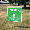 A 12x12-inch RAYGUN yard sign on a lawn that says, YOU DRINK WHAT YOU SPRAY, featuring an illustration of a spray bottle.