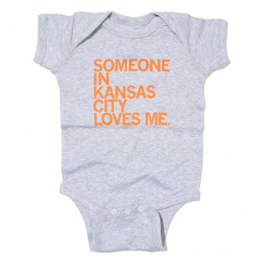 Gray RAYGUN baby onesie with the orange text SOMEONE IN KANSAS CITY LOVES ME.