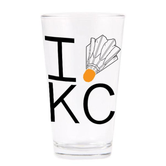 A clear glass pint glass with I [shuttlecock] KC printed in soy-based ink on the front.