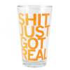 Clear dishwasher-safe pint glass with the orange text SHIT JUST GOT REAL printed on the front.