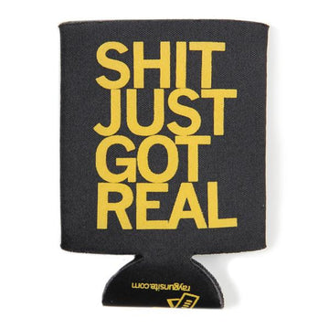 Black scuba foam drink koozie with the text SHIT JUST GOT REAL printed in large yellow gold plastisol ink letters.