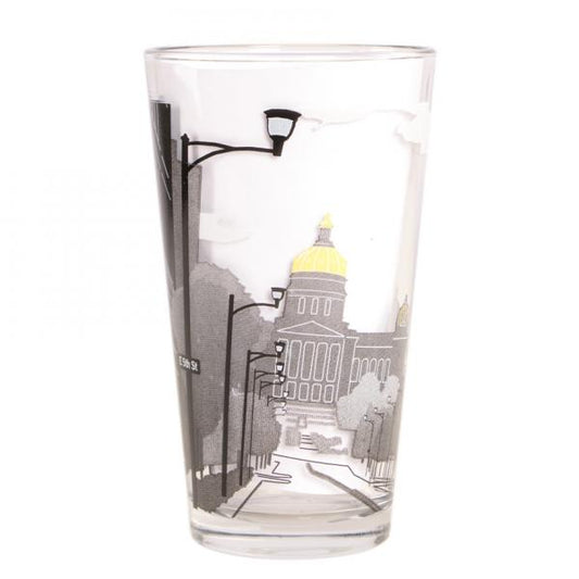 Clear pint glass featuring a black-and-white, soy-based ink graphic of a city street leading toward an Iowa Capitol building with a gold dome.