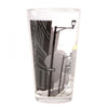A clear, American-made pint glass decorated with a black-and-white city street scene that includes a street sign reading E 5th St.