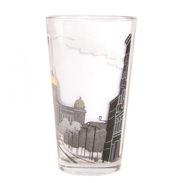 A clear Iowa Capitol pint glass printed with a black and white illustration of a city street and building with a gold-colored dome.