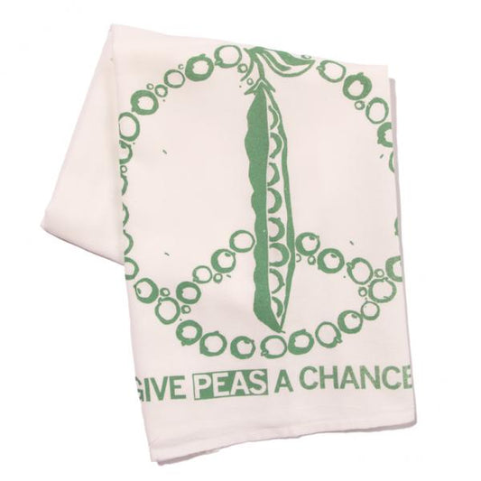 White flour sack kitchen towel featuring a green peace symbol made of peas, with the text GIVE PEAS A CHANCE printed at the bottom.