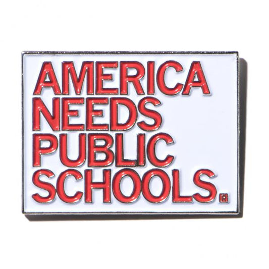 Rectangular enamel pin with a white background and red text that reads AMERICA NEEDS PUBLIC SCHOOLS.
