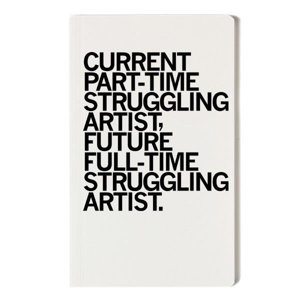 A white, screen-printed notebook with black text that reads, CURRENT PART-TIME STRUGGLING ARTIST, FUTURE FULL-TIME STRUGGLING ARTIST.