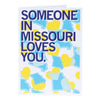 Folded greeting card with the text Someone in Missouri loves you over a background of blue Missouri state outlines and yellow hearts.