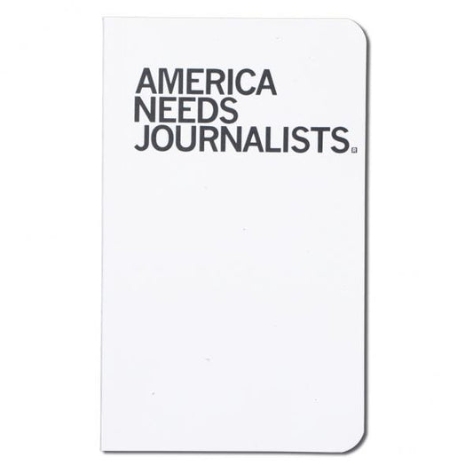 A white notebook with AMERICA NEEDS JOURNALISTS printed in black on the cover, produced as a Made in USA product.