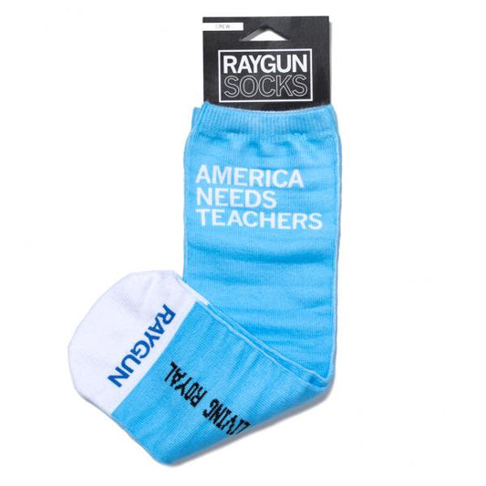 Light blue crew socks with AMERICA NEEDS TEACHERS printed in white, packaged with a Raygun Socks header card; these handmade socks are made in the USA.