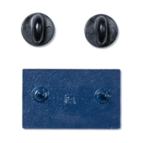 Back of a rectangular blue accountability enamel pin with two posts, shown alongside two black rubber clutch backings.