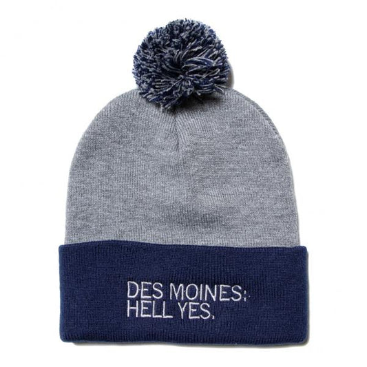 Grey RAYGUN beanie with a dark blue pom-pom and a dark blue cuff embroidered with the text DES MOINES: HELL YES.
