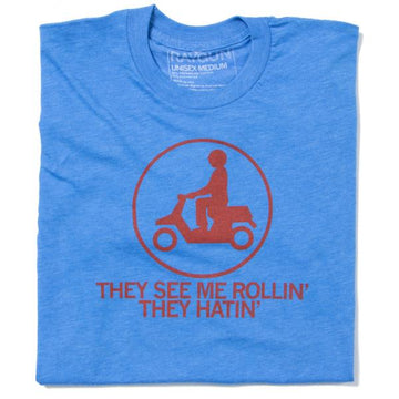 Blue Raygun t-shirt featuring a red icon of a person riding a scooter inside a circle, with the text THEY SEE ME ROLLIN THEY HATIN printed below.
