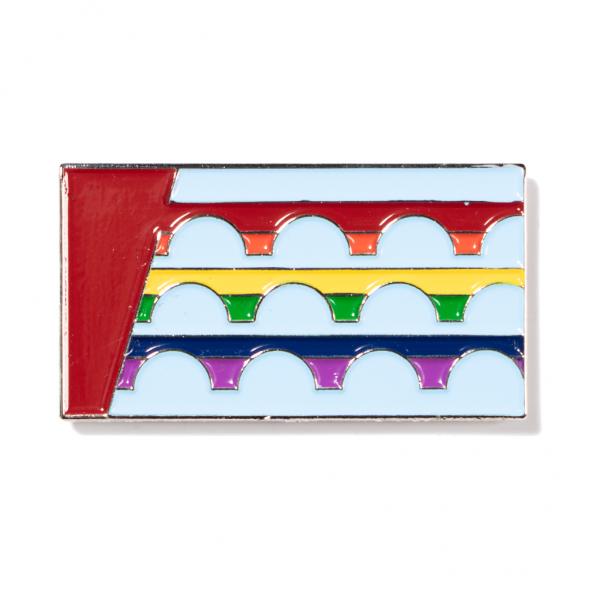 Rectangular RAYGUN enamel pin featuring a red vertical stripe on the left and three horizontal rows of rainbow-colored arches against a light blue background.