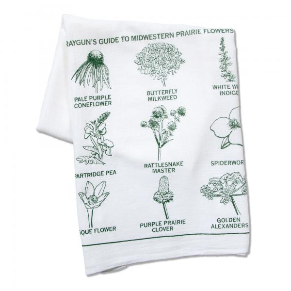 A white kitchen towel featuring a green illustration titled Rayguns Guide to Midwestern Prairie Flowers, with labeled drawings of various native wildflowers.
