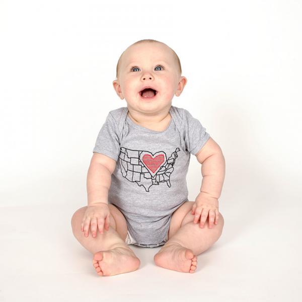 A baby wearing a union-made gray onesie featuring a map of the United States with a red heart over the Midwest.