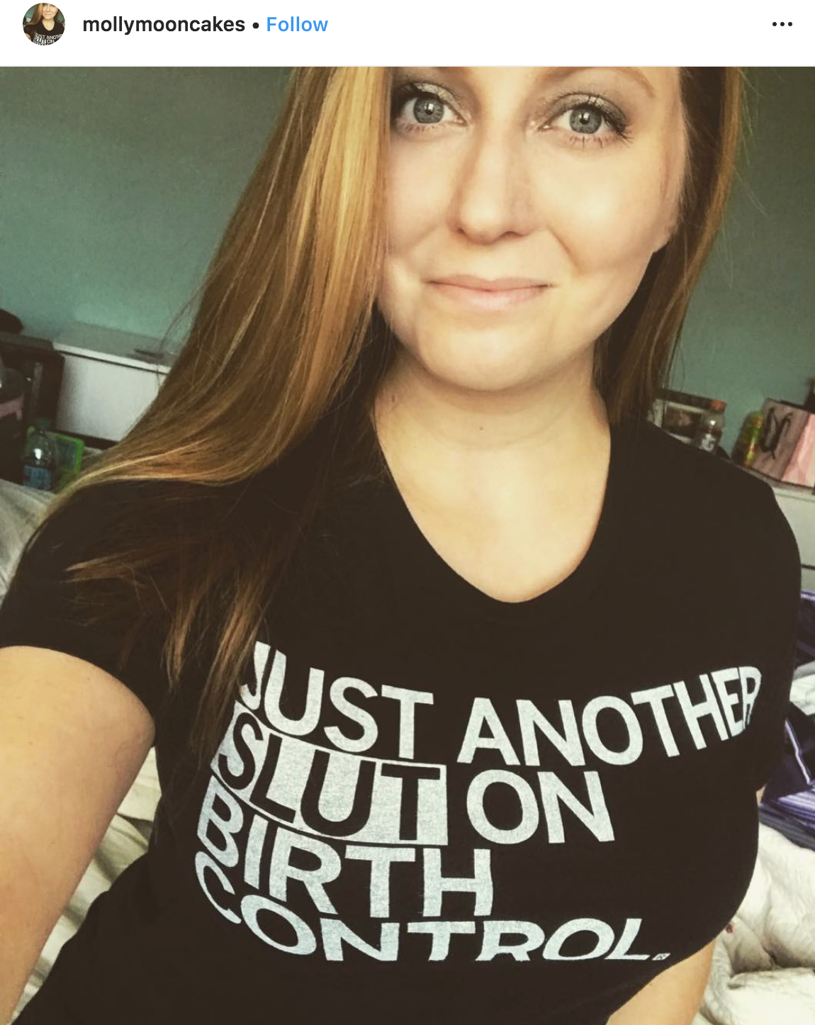 A woman wearing a union-made black t-shirt that says JUST ANOTHER SLUT ON BIRTH CONTROL.