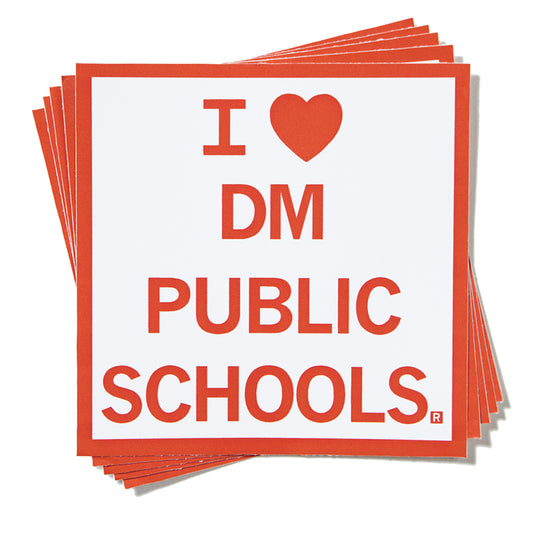 A stack of white square vinyl stickers that read I [heart] DM Public Schools in red text.